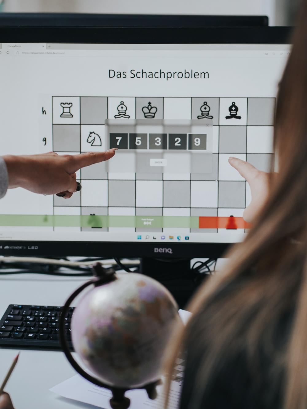 Ein Computer Bildschirm auf welchem ein Spiel zu sehen ist. Eine Hand deutet auf eine Zahlenreihenfolge.