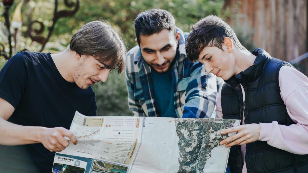 Drei junge Männer welche eine Landkarte lesen.