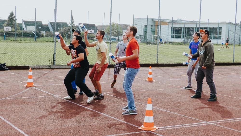Eine Gruppe junger Männer, welche auf einem Sportplatz stehen und ein Spiel spielen.